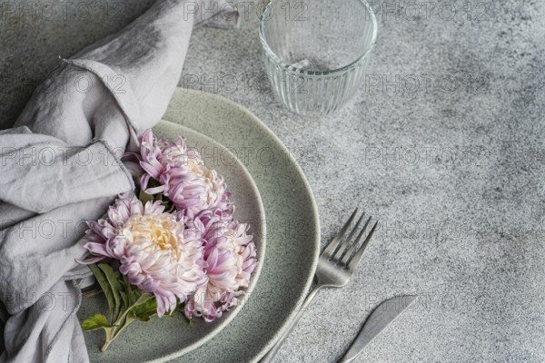 A soft, rustic dining setup features pink and cream chrysanthemums on ceramic plates with a linen napkin The cozy autumnal theme adds warmth to this elegant arrangement