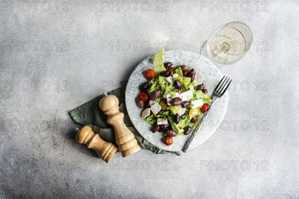A vibrant Greek salad with tomatoes, lettuce, fermented olives, feta cheese, and olive oil Accompanied by a glass of chilled white wine, perfect for a healthy meal