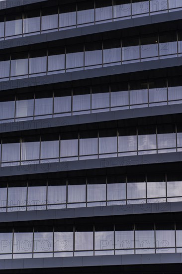 A detailed close-up showcasing the modern architectural design of a building's exterior. The image emphasizes the repetitive patterns and minimalist aesthetics of urban constructions