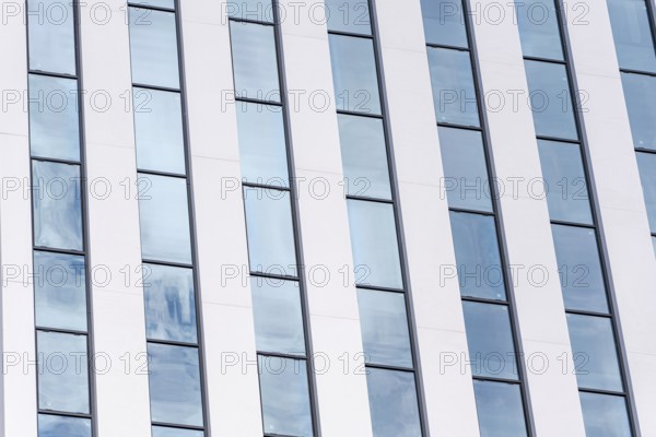 A detailed view of a modern building featuring a rhythmic pattern of white and glass vertical panels that exemplify contemporary architectural style and urban design