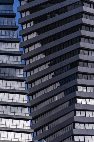 A detailed view of modern skyscraper exteriors featuring blue-tinted glass and staggered metal balconies
