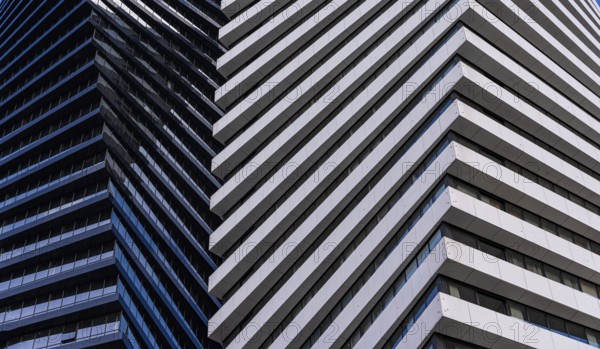 A close view of a modern skyscraper demonstrates contrasting architectural details, featuring alternating patterns of blue glass and white panels