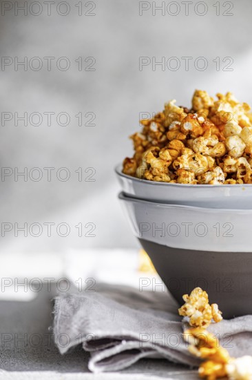 A bowl of sweet caramel popcorn on a grey napkin, background softly blurred