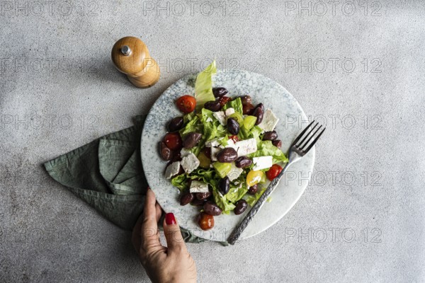 A vibrant Greek salad featuring tomatoes, lettuce, fermented olives, and feta cheese