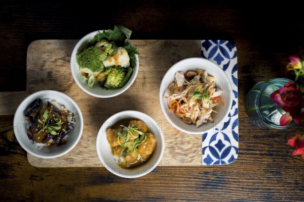 Gourmet bowls, chicken with glass noodles and peanuts, broccoli and cauliflower in satay sauce, tempura mushrooms in curry sauce, and aubergine stew over rice