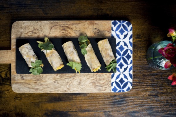 Delicious vegetable and courgette rolls elegantly arranged on a decorative wooden platter with cilantro garnish Perfect for showcasing gourmet appetizers in a culinary setting