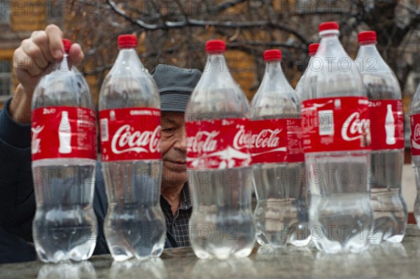 Sofia, Bulgaria. January 21st 2018 An old Bulgarian man filling Coca-Cola bottles with mineral water at a hot spring in the center or Sofia, Bulgaria