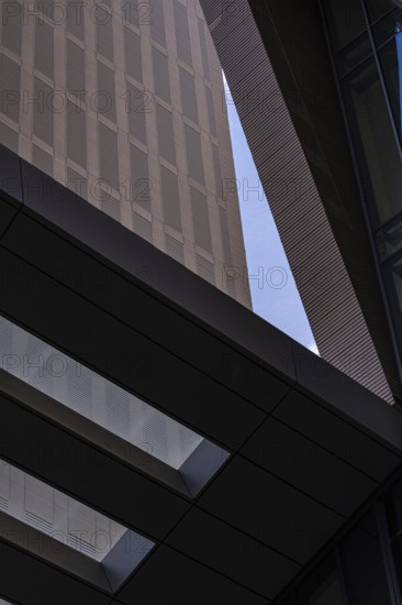 From below image captures the intricate textures and contrasting colors of modern architectural design, featuring a close view of a building's facade and its interplay with light and shadows