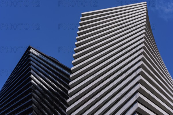 From below striking image of modern architecture showcasing geometric patterns and contrasting building designs against a clear blue sky
