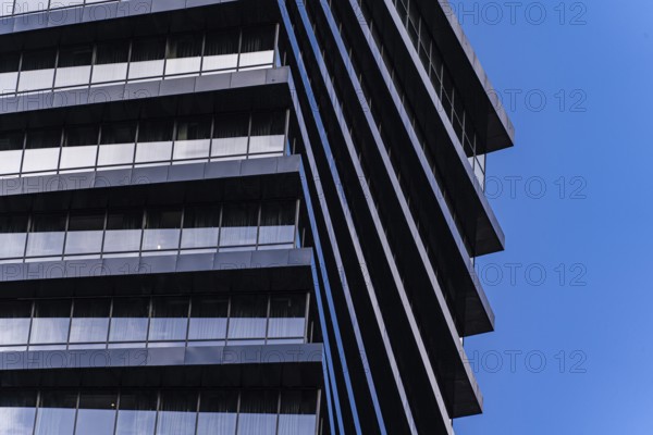 From below image highlights the geometric details of a modern skyscraper. The repeating patterns and sharp lines contrast dramatically against a clear blue sky