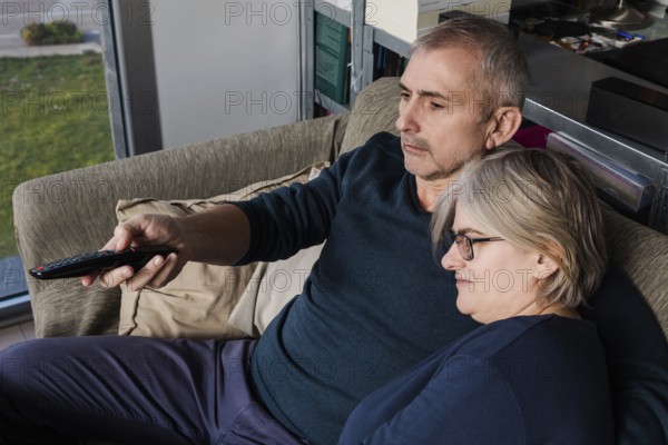 Senior couple relaxing on a comfortable sofa, enjoying a moment together while watching television The serene atmosphere emphasizes warmth and companionship