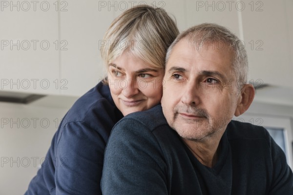 A senior couple embraces, displaying affection and warmth in a cozy home setting Their expressions reflect contentment and love, highlighting the beauty of long-term relationships