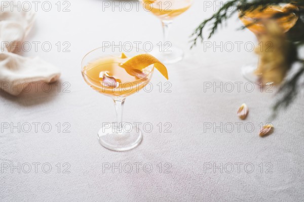 Elegant mandarin cocktail served in a stemmed glass, garnished with a twist of orange zest, on a textured white tablecloth. Subtle lighting enhances the soothing ambiance, perfect for a refreshing moment