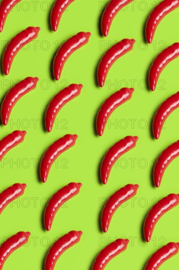 Vibrant, glossy red plastic peppers on a bright green background symbolize artificiality in diet and junk food culture, highlighting sustainability concerns and consumerism