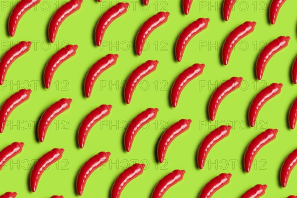 Rows of bright red plastic peppers on a bold green background This image critiques junk food culture and highlights artificial diets through vibrant colors and patterns