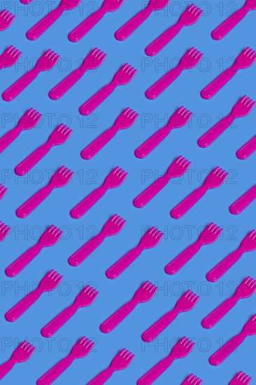 Rows of pink plastic cutlery on a blue background symbolizing the artificiality and environmental impact of modern junk food culture Highlights the critique on disposable consumption