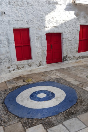 Bright red doors and white wall of typical traditional architecture with a blue and white symbol to ward of envy, a pretty street in the Turkish old town of Bodrum, Turkish Aegean coast of Turkey