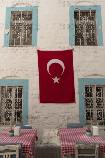 Bodrum, Mugla, Turkey. April 23rd 2022 Pretty cafe tables set against a beautiful pastel blue painted old building in the side streets of Bodrum old town, a popular trendy tourist destination in south west Turkey