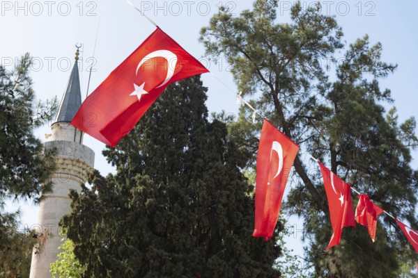 Bodrum, Turkey. April 23rd 2022 Turkish national flag fluttering in front of an Islamic minaret of a mosque in the popular tourist town of Bodrum, Mugla, Turkey