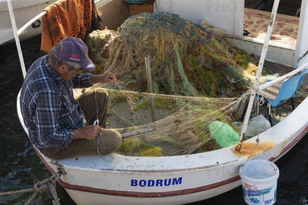 Bodrum, Mugla, Turkey. April 23rd 2022 A fisherman mending nets on his boat in Bodrum town harbour, the Aegean seaside location in Turkey is a popular Turkish tourism destination