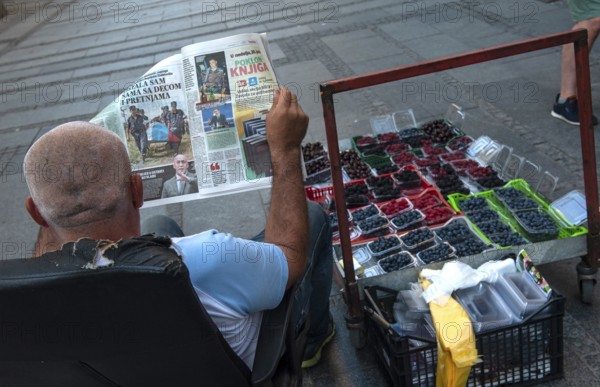 Belgrade, Serbia. July 27th 2019 A Serbian man reading a newspaper while selling fruit on the street in Belgrade