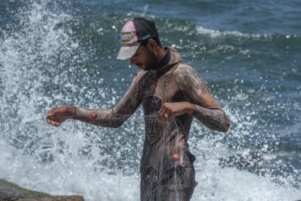 An young Egyptian fisherman wearing a wetsuit arranges his net on the Mediterranean Sea front of Alexandria, second largest city in Egypt