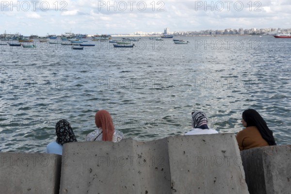 Alexandria, Egypt. December 2nd 2022 Egyptian Muslim Women sit on large concrete blocks designed to prevent flooding due to rising sea levels caused by global warming, Alexandria, Egypt
