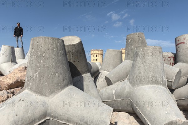 Alexandria, Egypt. December 1st 2022 Young Egyptian man standing on massive concrete blocks designed to protect the Mediterranean Sea front from flooding and rising sea levels in Alexandria, Egypt