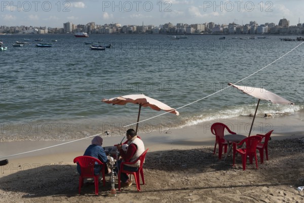 Alexandria, Egypt. December 1st 2022 An Egyptian couple sit on the receding Mediterranean beach of the Egyptian city of Alexandria in the northern Delta of Egypt