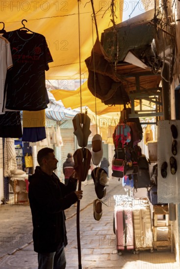 Tunis, Tunisia 4th May, 2024 A Tunisian man hanging traditional slippers outside of a shop in the souk of Tunis Medina, a busy shopping market for locals and tourists, Tunisia, North Africa