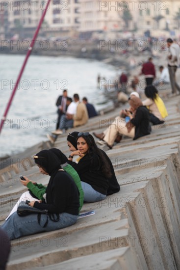 Alexandria, Egypt. December 1st 2022 Young Egyptian women sit on concrete sea defence walls in the Mediterranean coastal city of Alexandria in the north delta region of Egypt