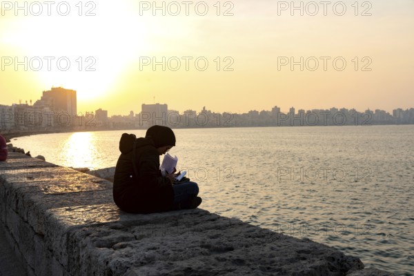 Alexandria, Egypt. December 1st 2022 A Muslim Egyptian female student studying on the corniche Mediterranean sea front near the Bibliotheca Alexandrina, Alexandria, Egypt