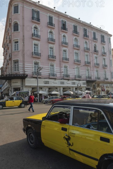 Alexandria, Egypt. December 4th 2022 A black and yellow Alexandria taxi in the street outside the famous once Greek cafe The Trianon and Paradise Inn, Le Metropole Hotel, Saad Zagloul Sq, Alexandria, Egypt