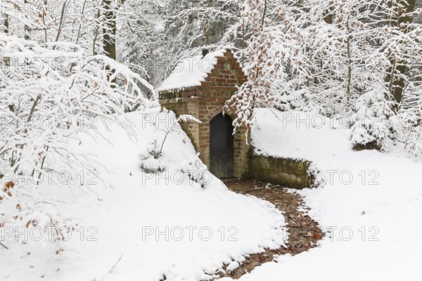 Small water spring with house in snow, Thrarandter Wald, Saxony, Germany