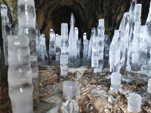 Tall icicles stretch out in a dark cave with stony walls, winter, hiking in the Franconian Forest nature park Park