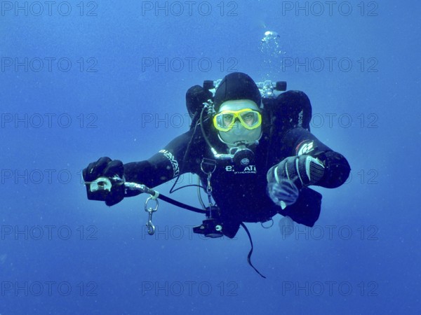 A diver with complete diving equipment extends the second controller to his dive partner, who has apparently run out of air, to share his air. Wreck of the Vis dive site, Pula, Croatia, Mediterranean Sea