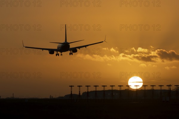 Boeing 737 commercial passenger airliner jet aircraft of Ryanair airways in flight on approach to land over runway lights at sunset at London Stansted airport, Essex, England, United Kingdom