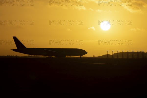 Boeing 777 A7-BFL commercial jet aircraft of Qatar cargo waiting to take off silhouette at sunset at London Stansted airport, Essex, England, United Kingdom