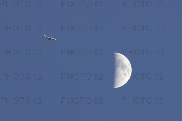 Airbus commercial passenger airliner jet aircraft of British airways in flight with the moon in the background, England, United Kingdom