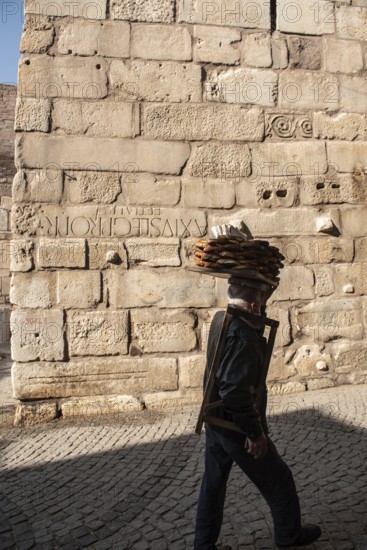 Ankara, Turkey. November 17th 2020 Simit seller walking past old city walls with Roman numerals carved in the stone, Ankara Castle, Turkey