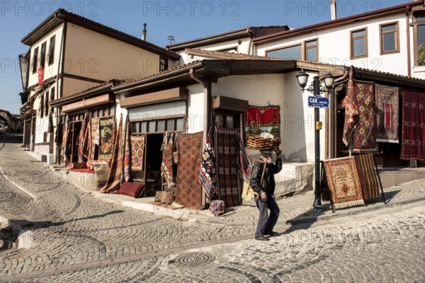 Ankara, Turkey. November 17th 2020 Traditional Turkish Simit seller walking past Antique carpet shops in Ankara Castle, Turkey