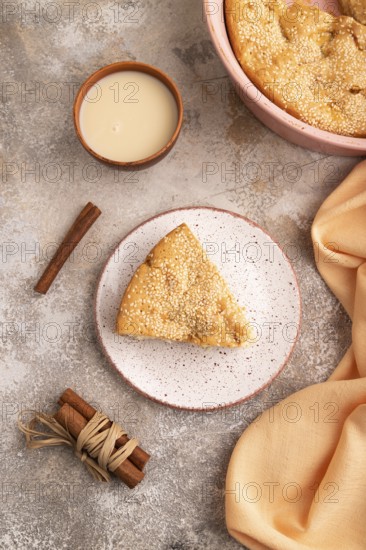 Apple Charlotte cake on brown concrete background and orange linen textile, cup of milk, top view, flat lay, close up
