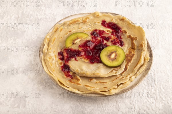 Stack of Plain Fried pancakes with jam and kiwi on gray concrete. side view, close up
