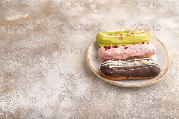 Glazed Eclairs on brown concrete on brown concrete, side view, copy space
