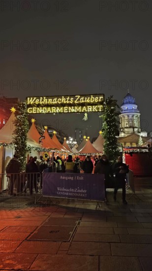 Christmas market at Gendarmenmarkt at night with bright lights and many visitors in a festive atmosphere, Berlin