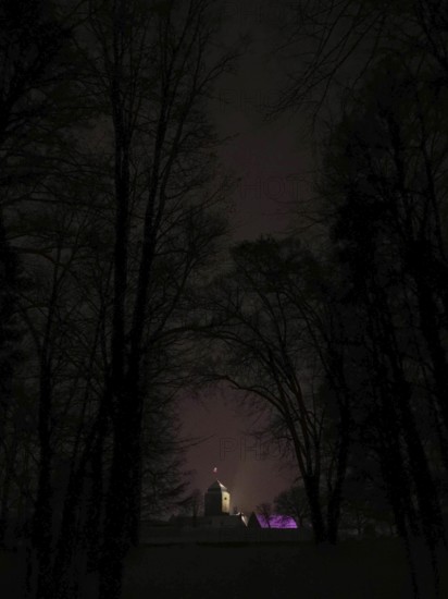 Building hidden in the dark, dimly lit Rosenberg Fortress surrounded by trees, Kronach, Frankenwald nature park Park