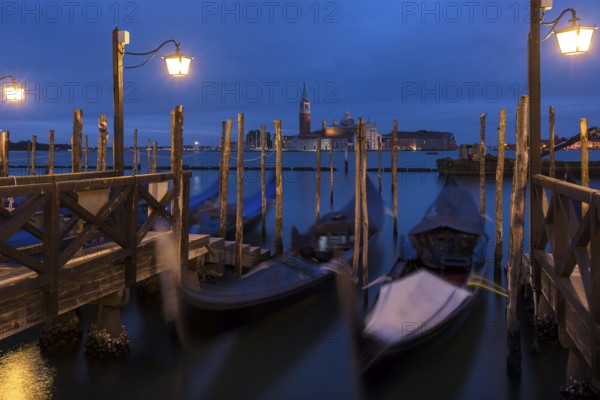 Nighttime atmosphere with moving gondolas, San Georgio Maggiore in the back, Guidecca Island on the right, Venice, Italy