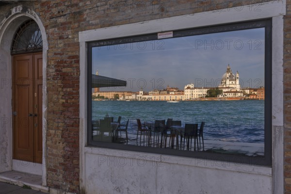 Santa Maria Salute is reflected in a shop window on the island of Guidecca, Venice, Veneto, Italy