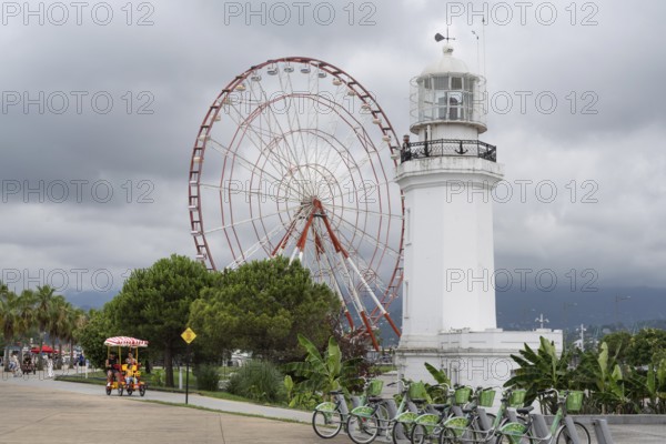 Batumi, Georgia. July 21st 2025. A light house and Ferris wheel with parked bicycles for hire on the sea front esplanade on the Black Sea coast of Georgia