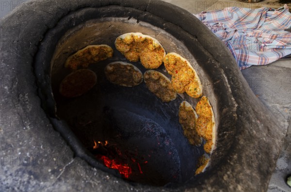 Delicious Turkish Biberli Ekmek Flat bread with red pepper paste cooking in a traditional oven in Antakya Hatay, Turkey